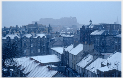 Rooftops with snow and dim castle beyond.