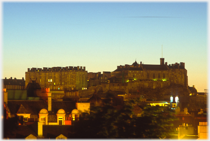 Castle silhouetted against orange and blue-green sky.