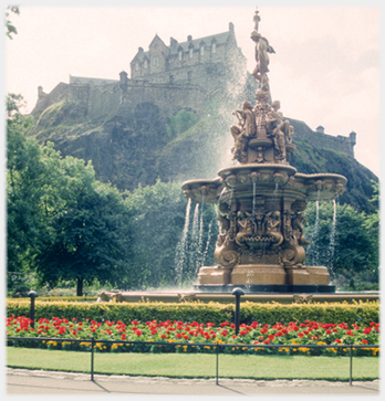 Fountain with castle on rock above it.