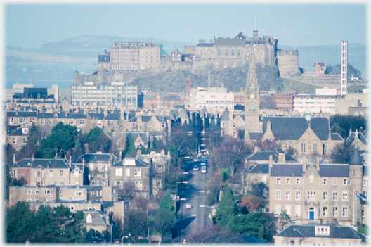 Street pointing to castle with land behind it.