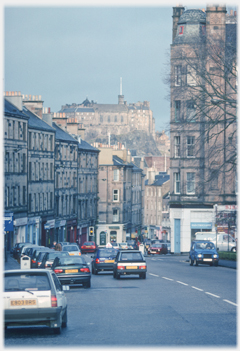 Looking down a street with tenements on both sides and the castle ahead.