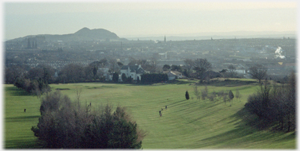 Golf course with brown grass, Arthurs Seat and city.