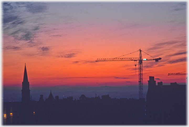 Sunset with crane and spire.