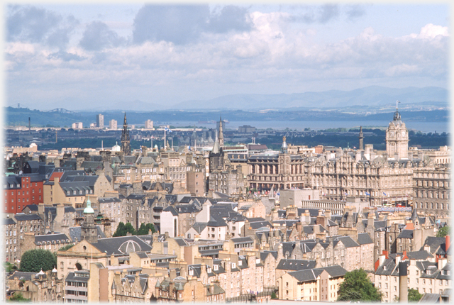 City centre rooftops with estuary and mountains beyond