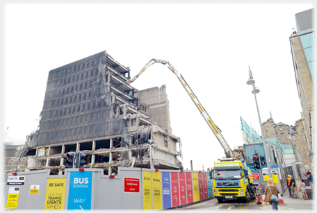 Truck based demolishion crane attacking half gone building.