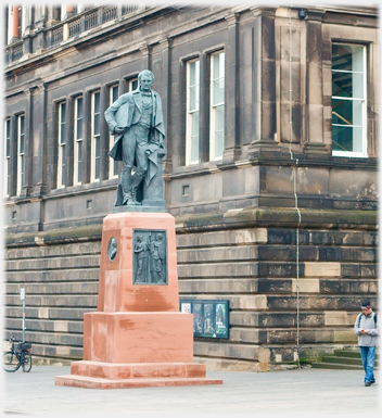 Statue on large plinth in front of building.