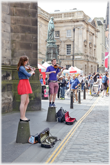 Two violinists on bollards.