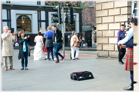 Same man and woman taking photograph of piper.