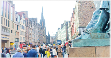 Statue's feet and throngs looking up High Street.