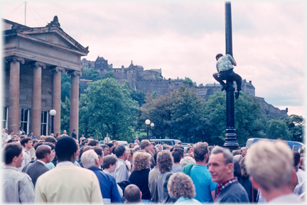 Man being watched climbing lamppost.