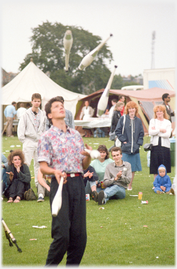 Man with three batons in the air and one in his hand.