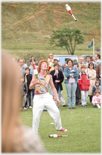 Man with three batons in the air and one on the ground.