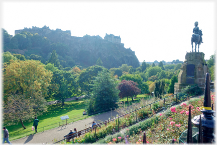 View over tree tops to the castle with hoorseman statue to right.