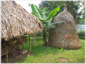 Hay stack next to a thatched roof.