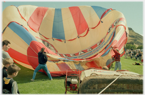 Two people struggling with inflating balloon.