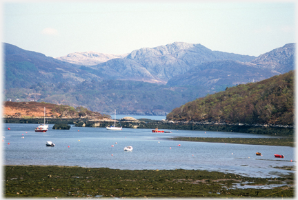 Boats in sheltered area with background of craggy hills.