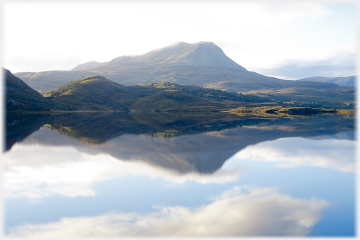 High hill with lower foreground hills reflected in the loch.