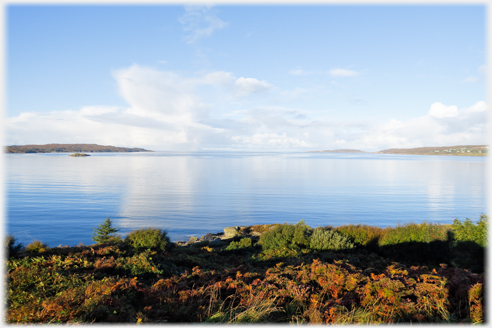 Wide bay with headlands and clouds reflected in water.