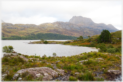 Scrubby foreground with loch and hill beyond.