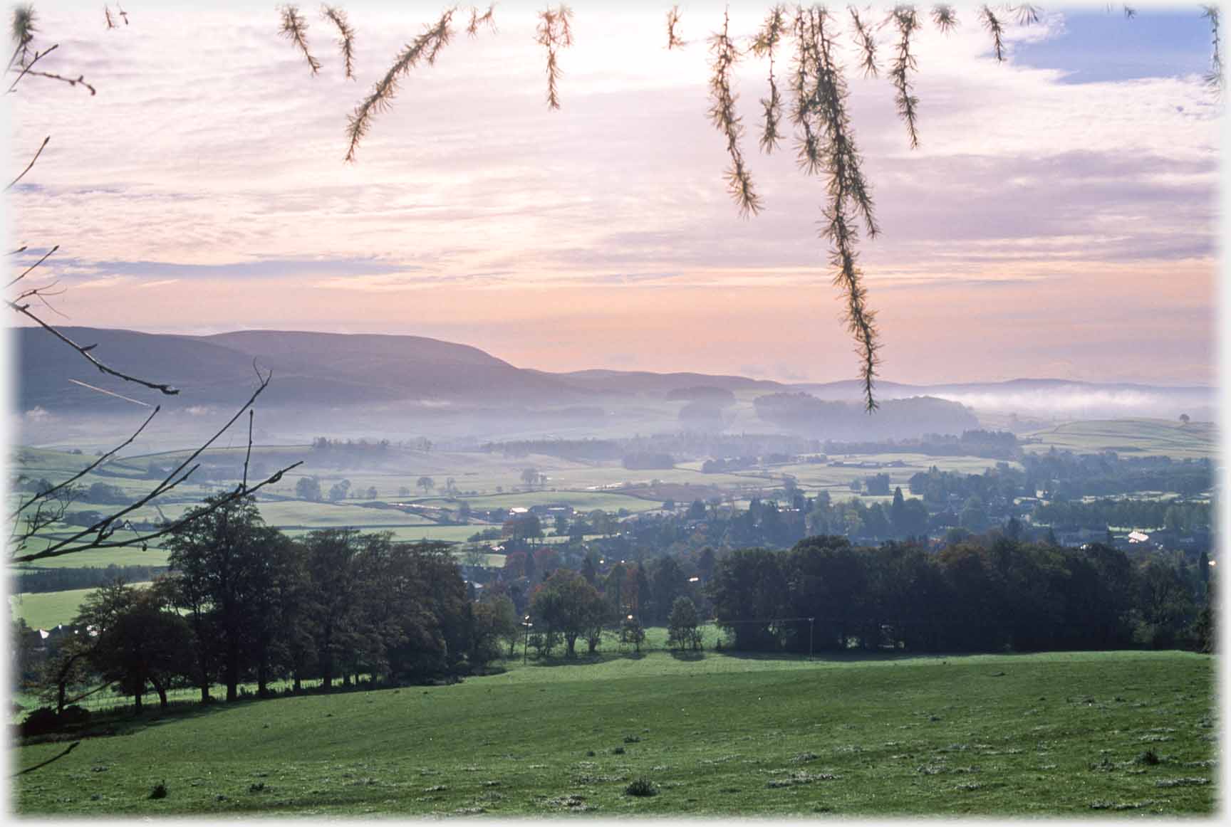 Thin lines of mist beginning to hang over wide valley.