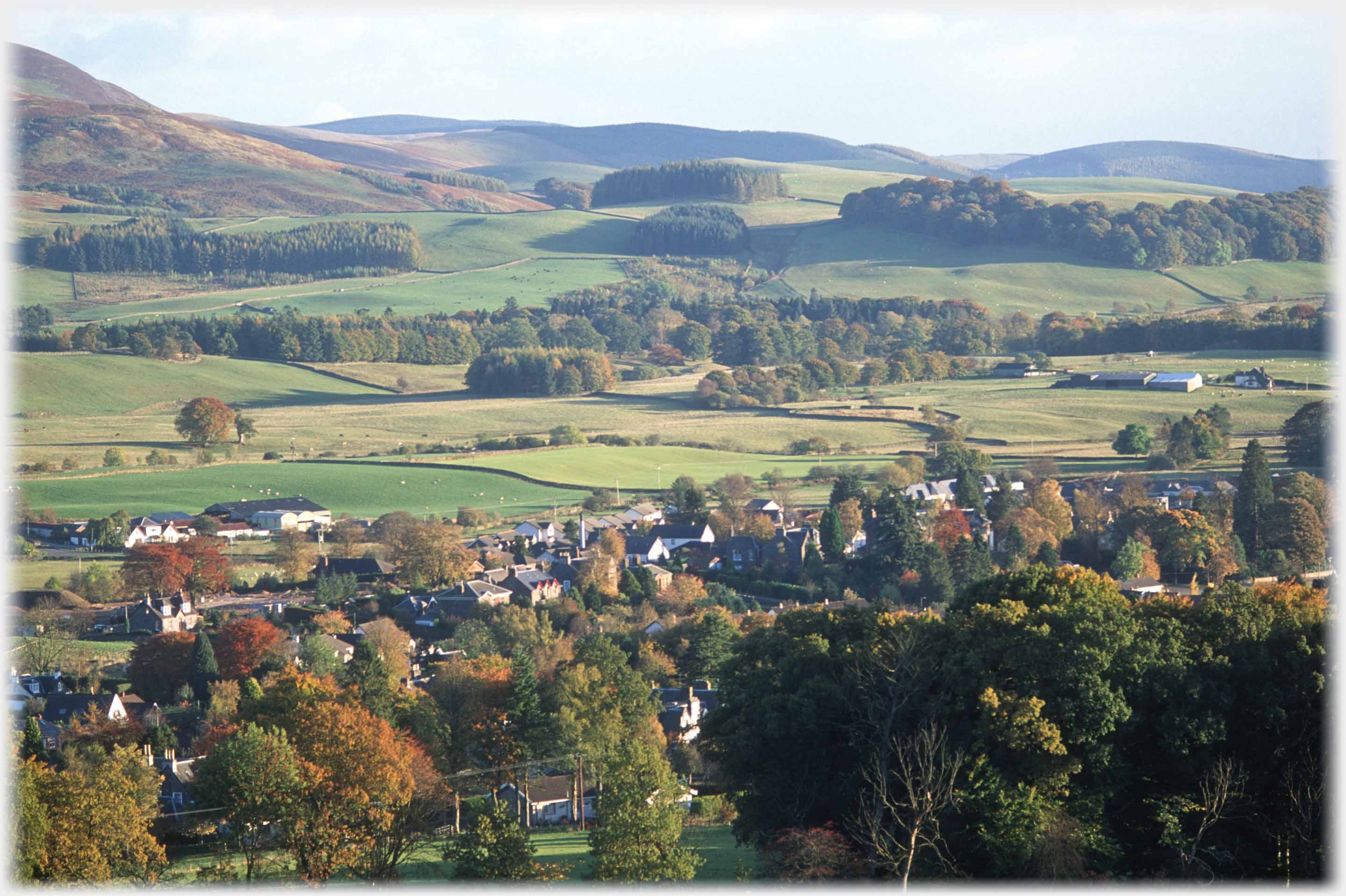 Looking down over town onto valley with tried slopes and hills beyond, autumn colours starting.