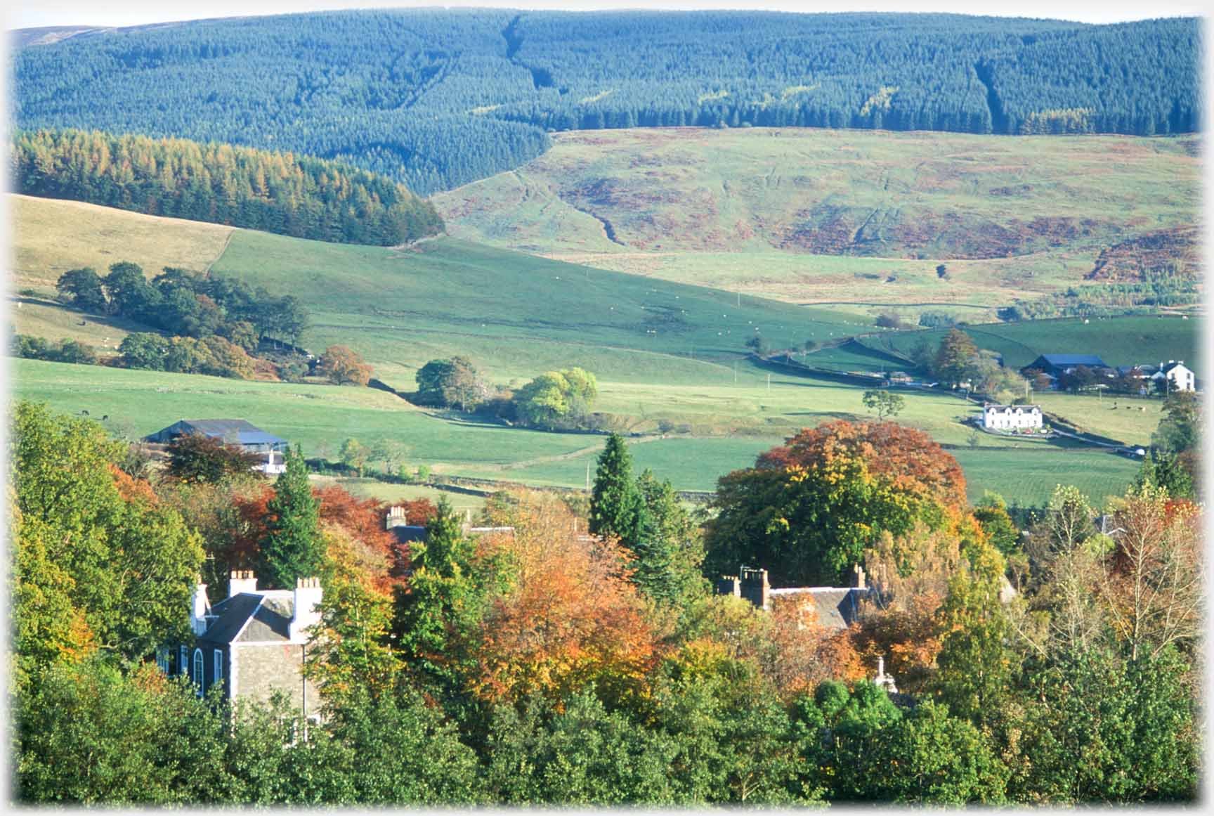 Treed fields and hills beyond, wall of ruin visible.