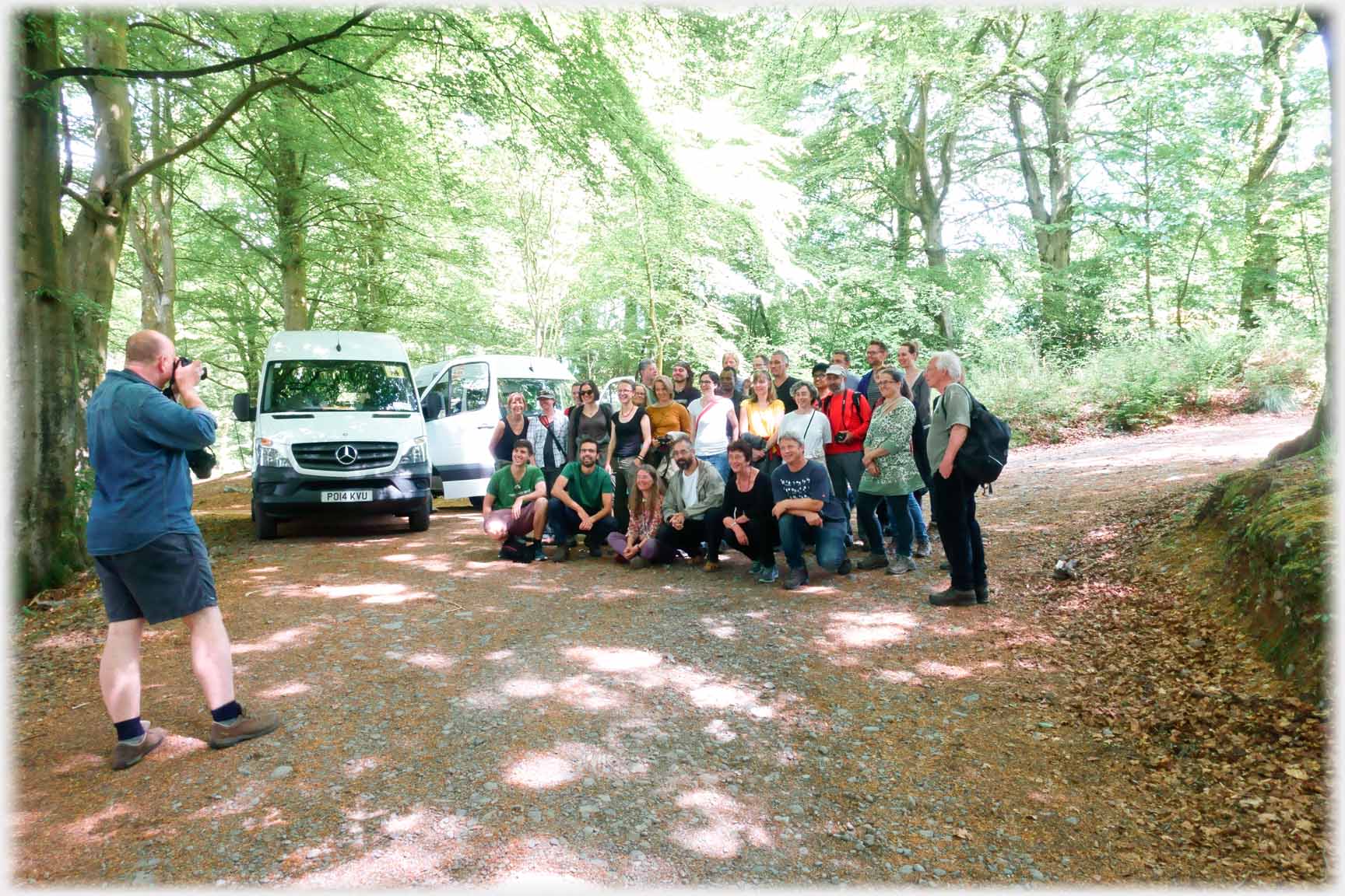 Group of people posing for photographer by two vans.