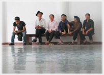 Line of people on bench waiting.