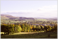 Autumn landscape with hills to left and town in foreground.