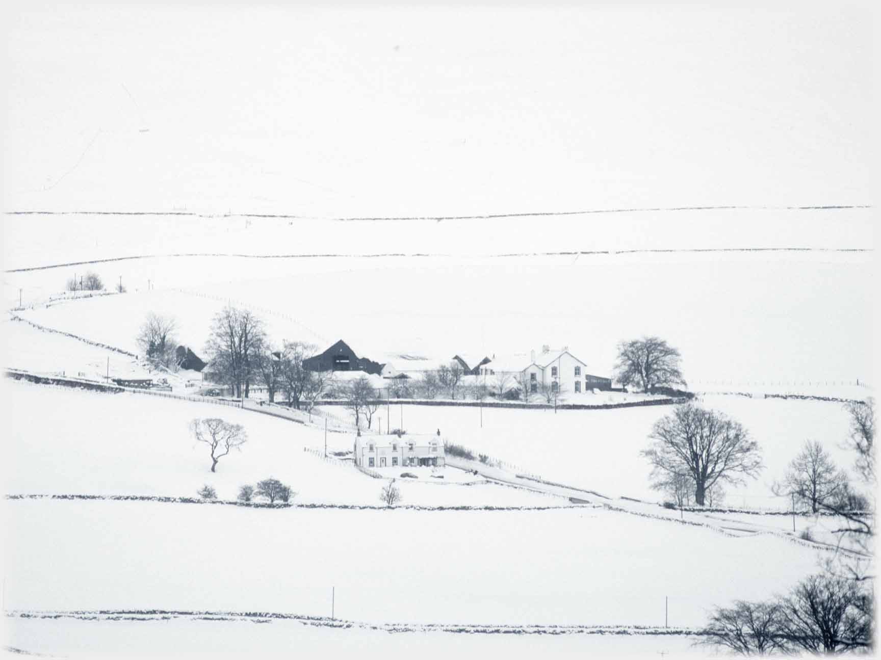 Fields cottages, farm and hillside in snow.