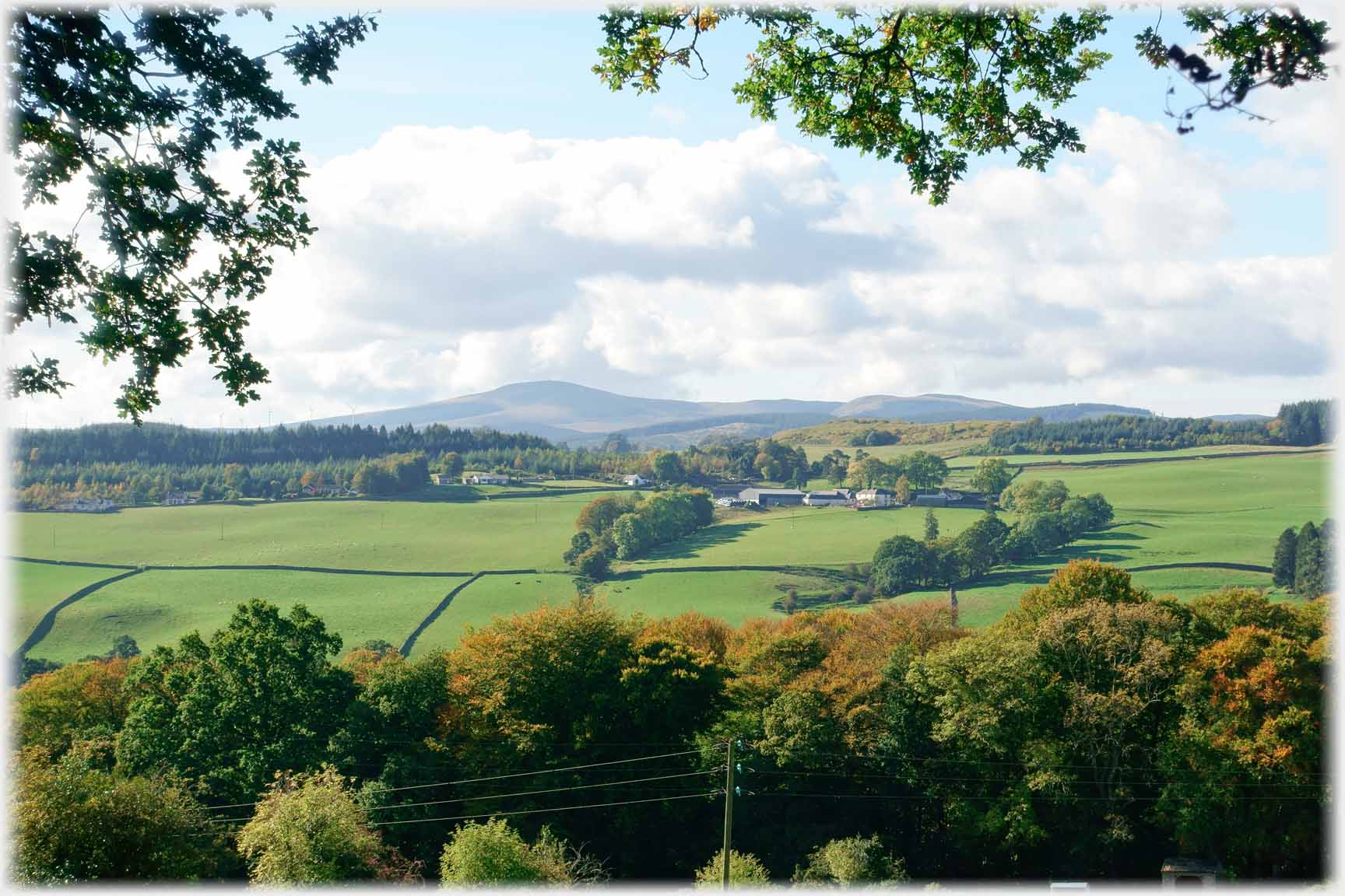 Late summer view of farm, hillside, and distant hill.