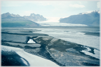 Black shore, sea and glacier between mountains.