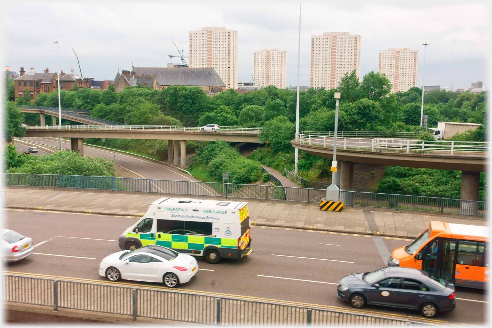 Intersecting motorway lanes with tower blocks in the background.