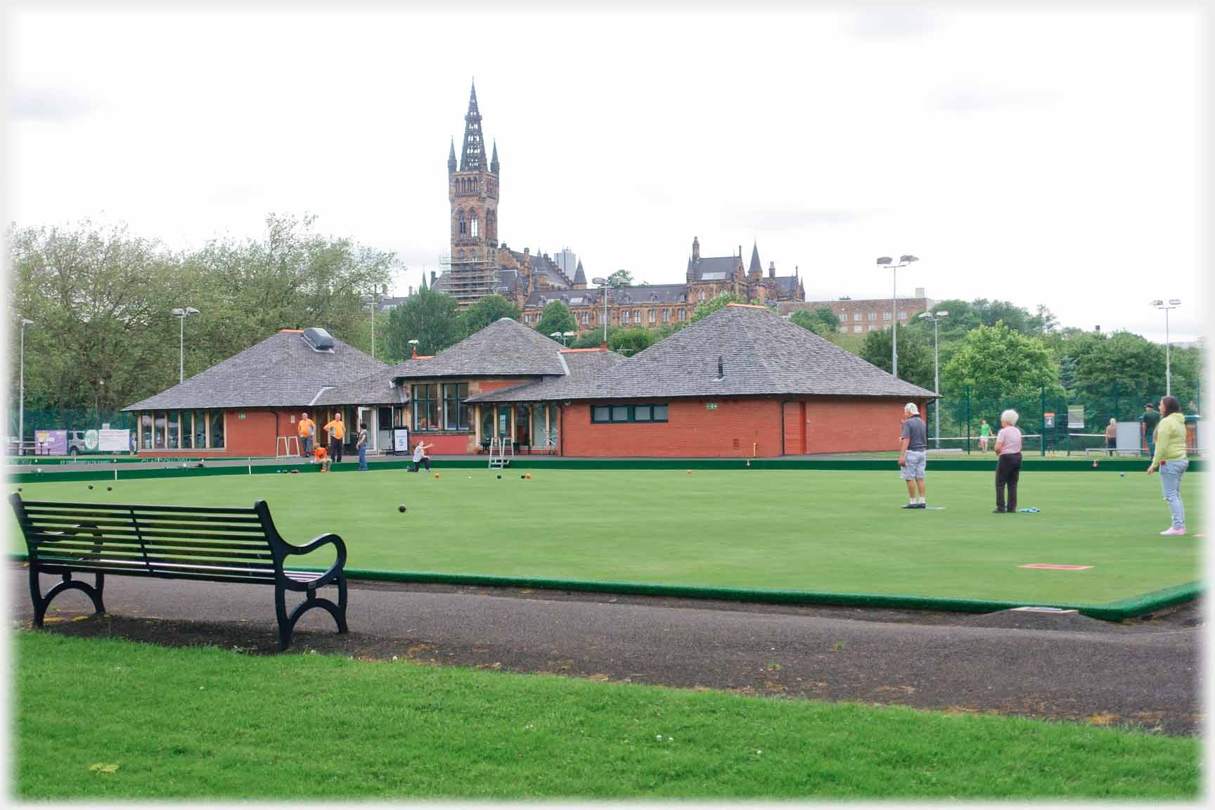 Bowling green with university buildings including tower behind.