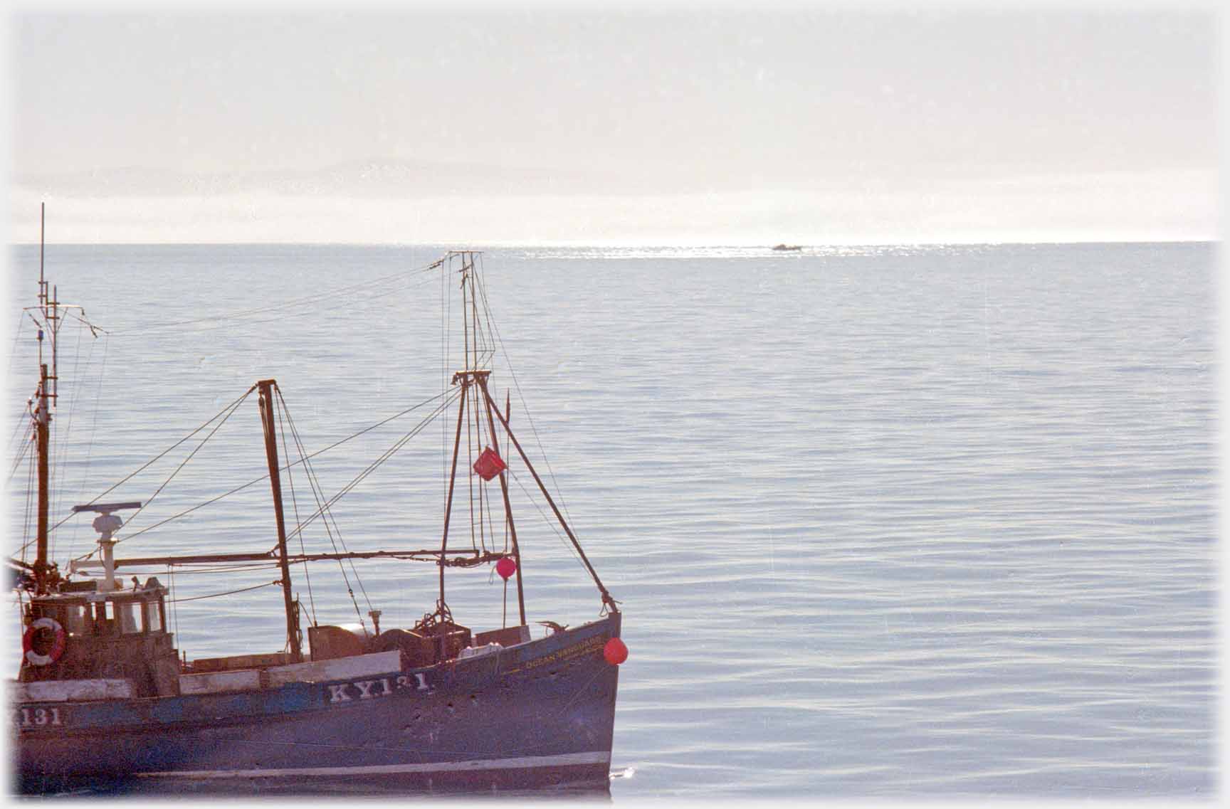 Boat in foreground, distant boat in patch of sun.