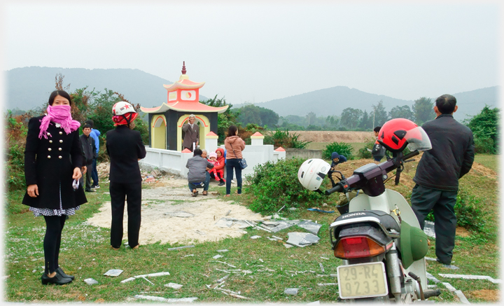 New tomb, people standing and a motorbike.