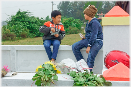 Two teenage cousins on tomb wall playing cards.