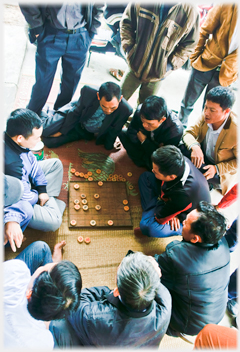 Men gathered round a game of Chinese chess.
