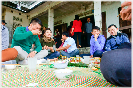 Group sittingon mats eating.