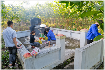 Arranging offerings on tomb.