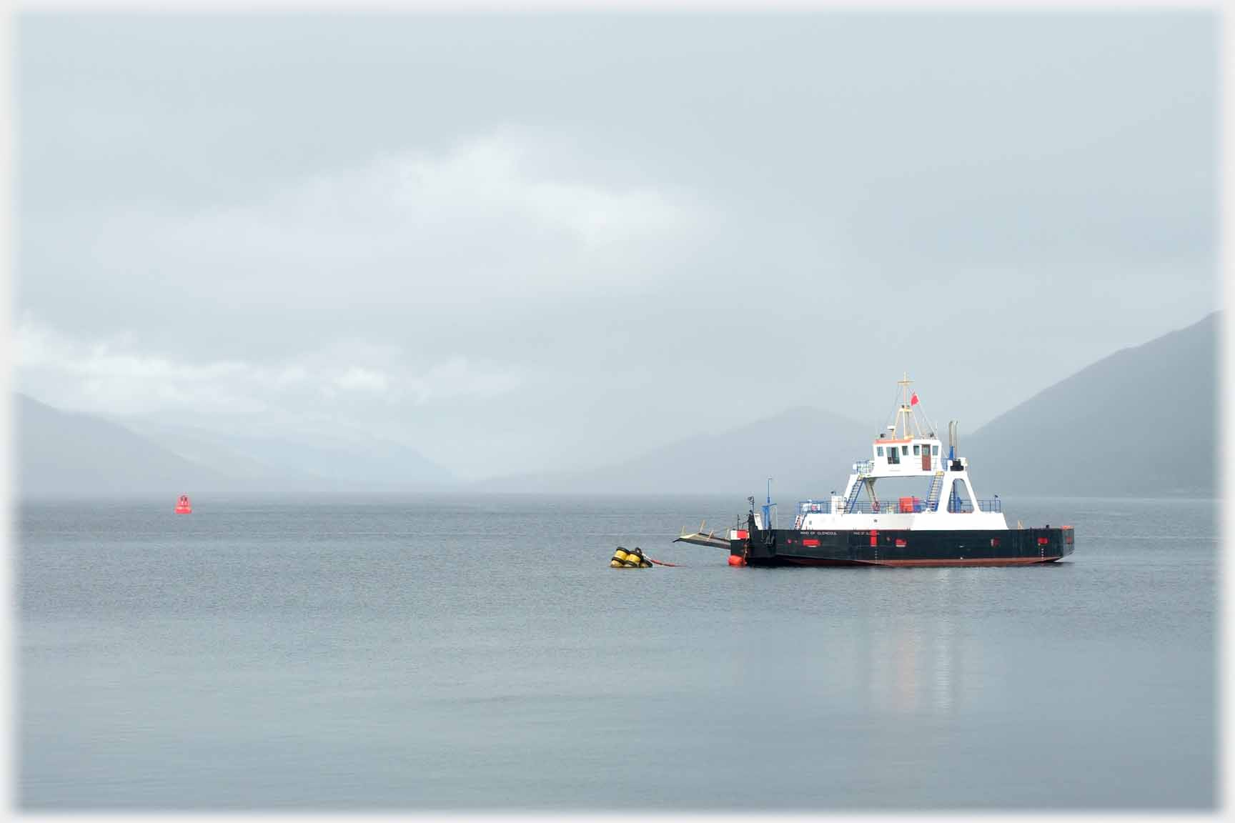 Ferry moored offshore, background hills veiled in drizzle.