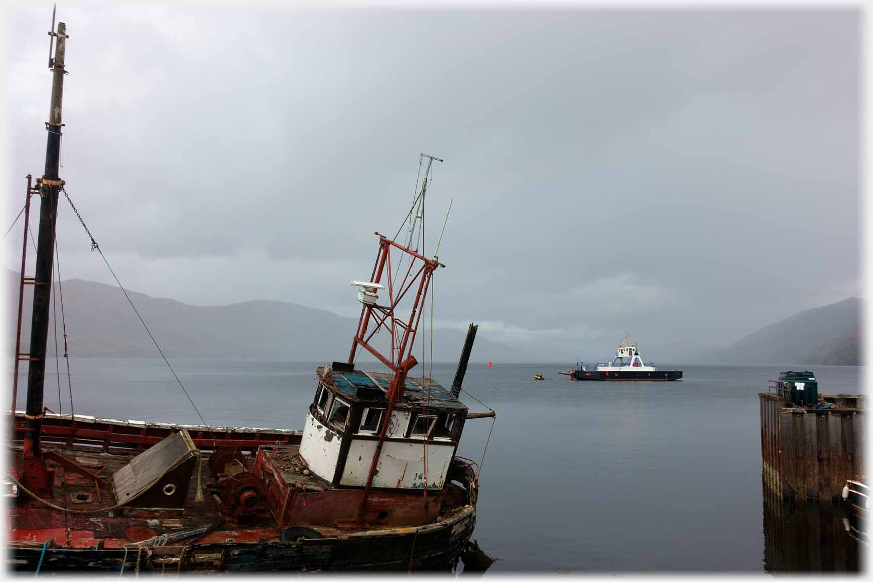 Looking past beached boat at ferry moored offshore.