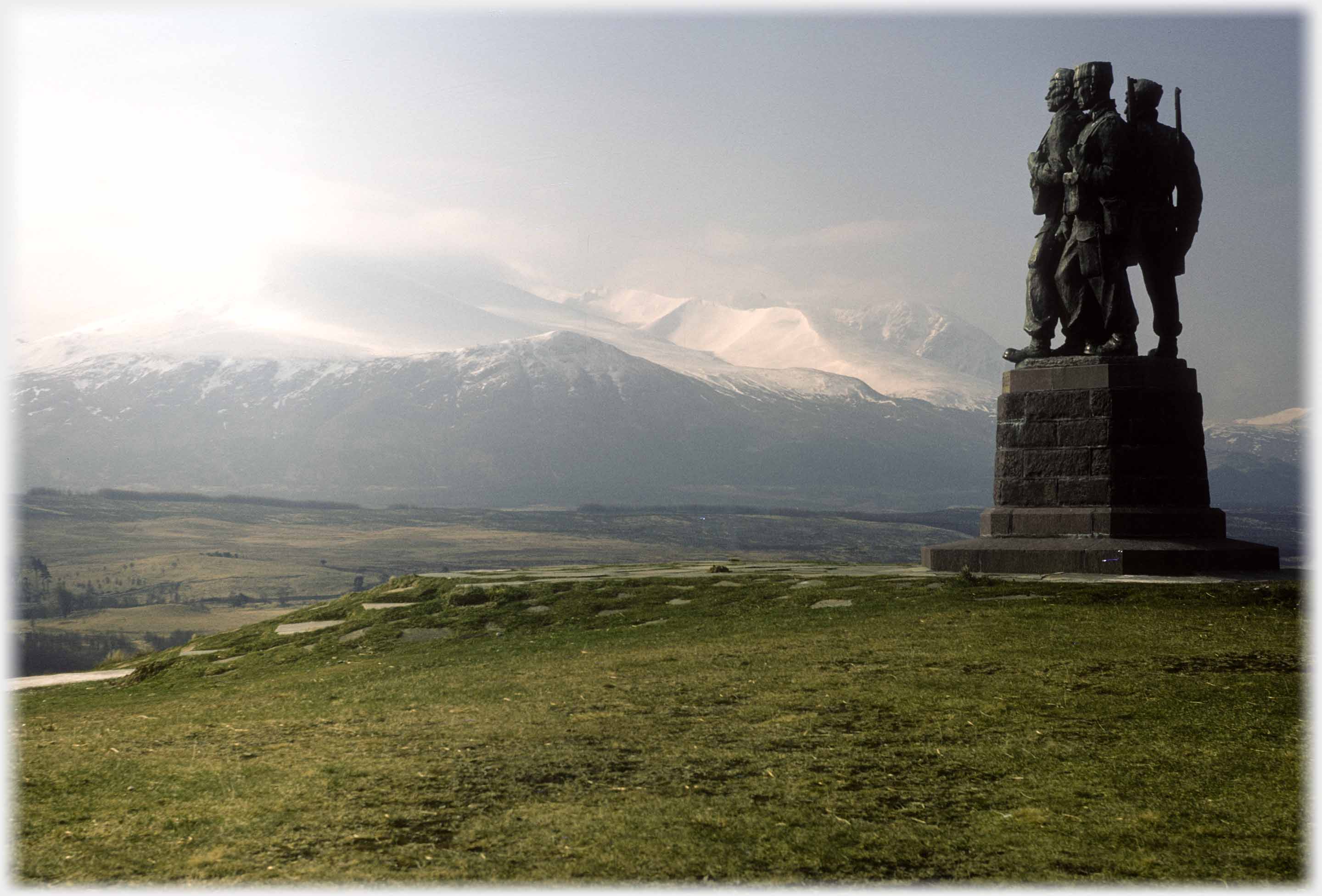 Plinth with three soldiers looking towards snow covered mountains.