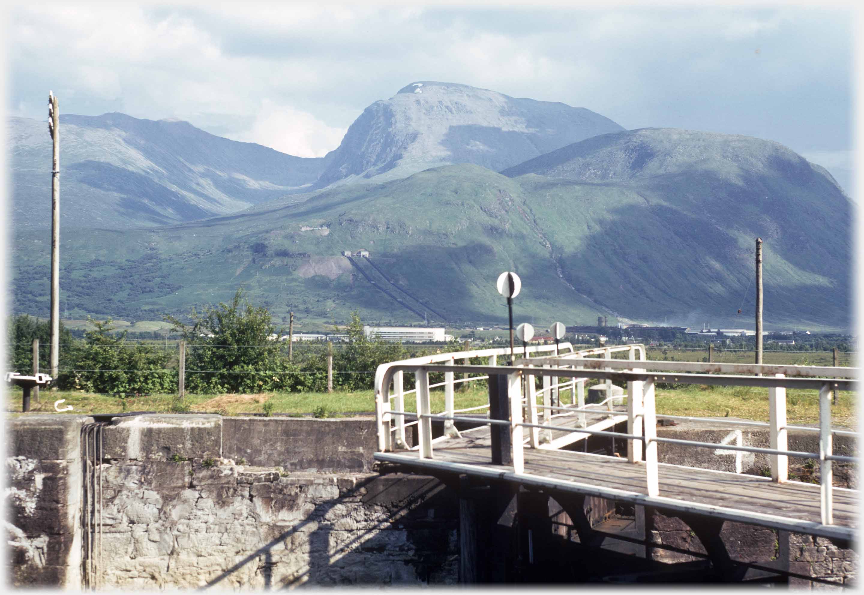 Full unclouded view of bulky mountain with lock gates in foreground.
