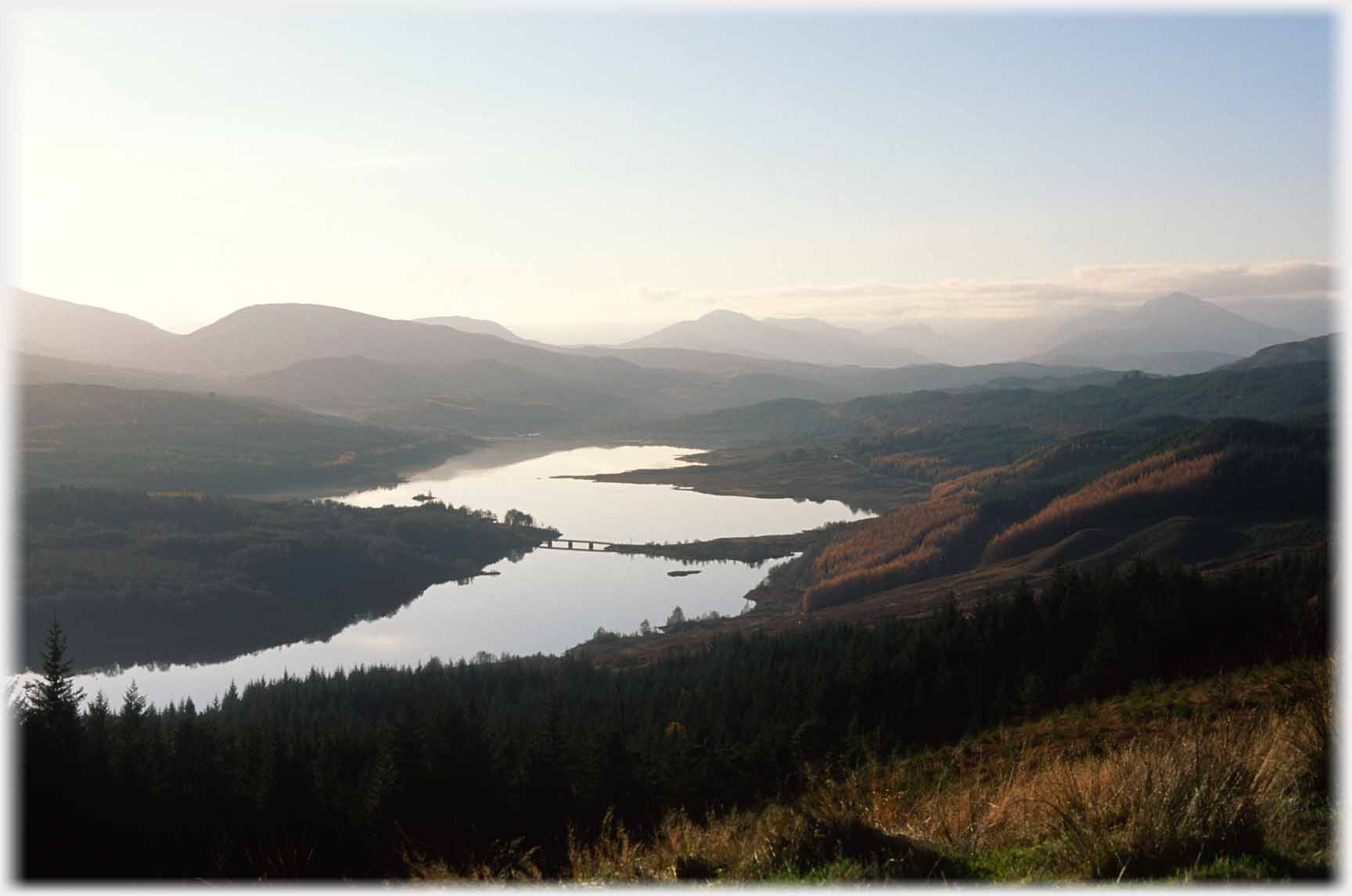 Loch twisting away with bridge over narrows in distance.