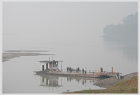 Ferry with passengers bording against misty river.