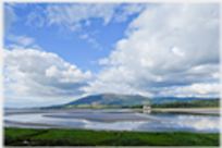 Hill seen across estuary with clouds.