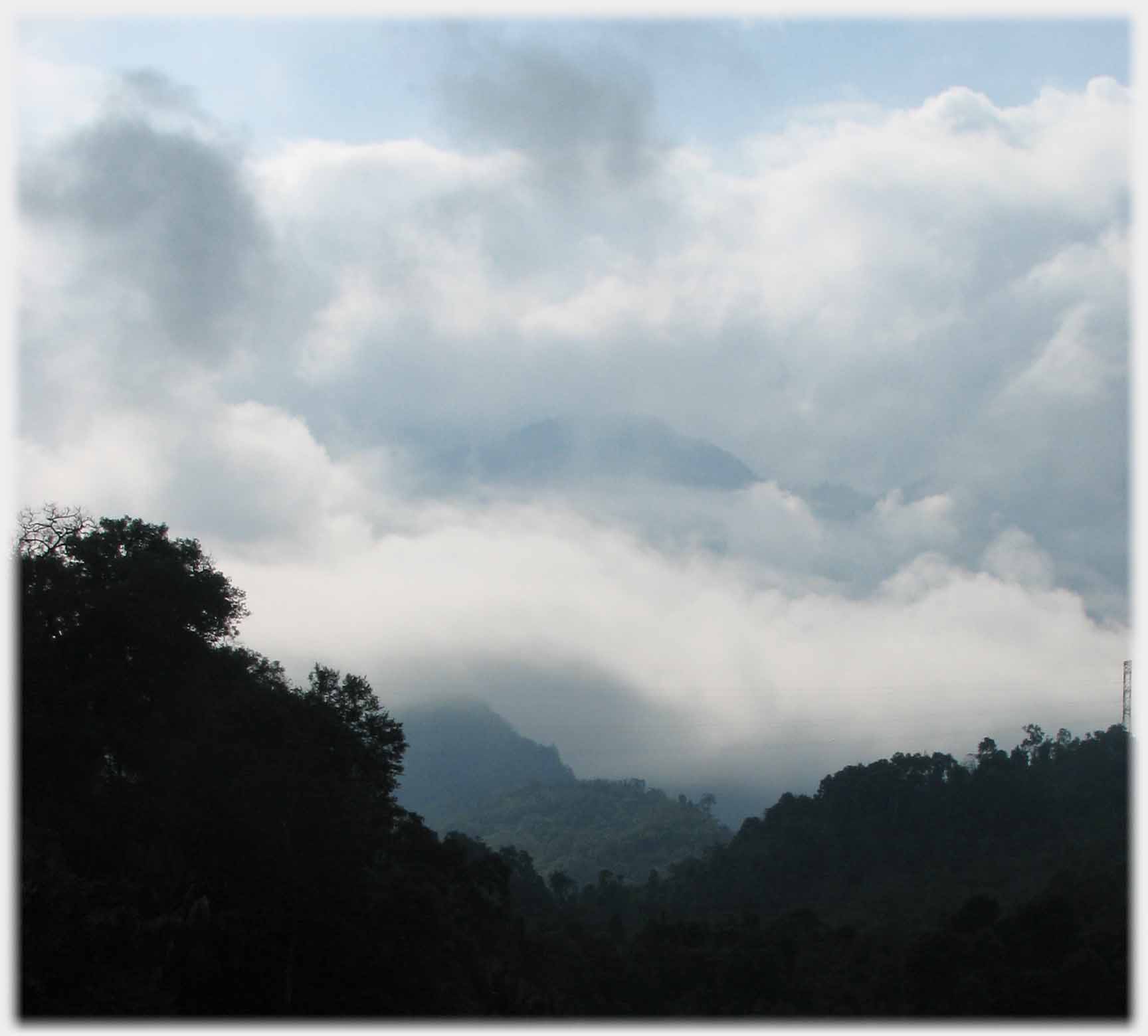 Clouds around mountain and wooded hills.