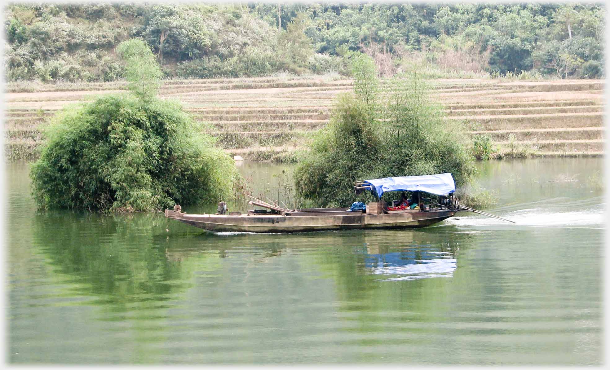 Closer view of same boat showing shrubs are in the river.
