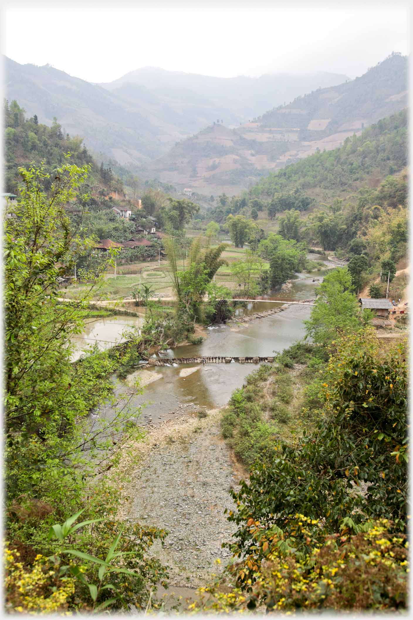 Vertical view of river with footbridge.